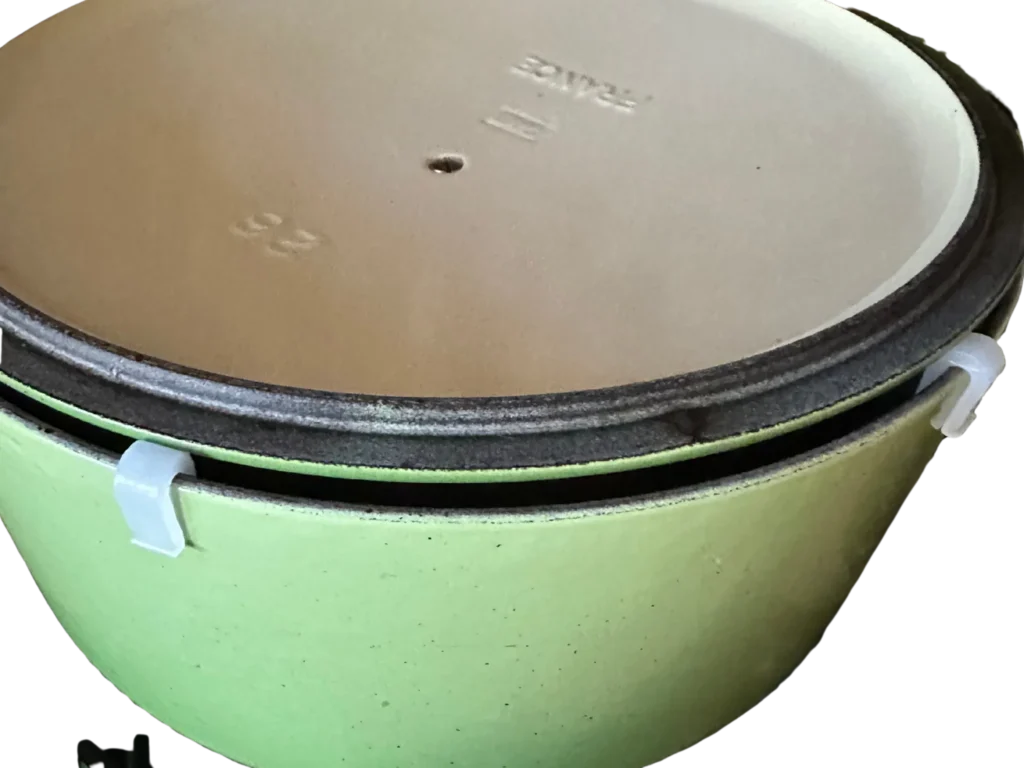 Le Creuset Lid Spacers shown clipped to a palm green colored dutch oven with the lid inverted on top of the oven allowing air circulation and scratch resistance when storing.