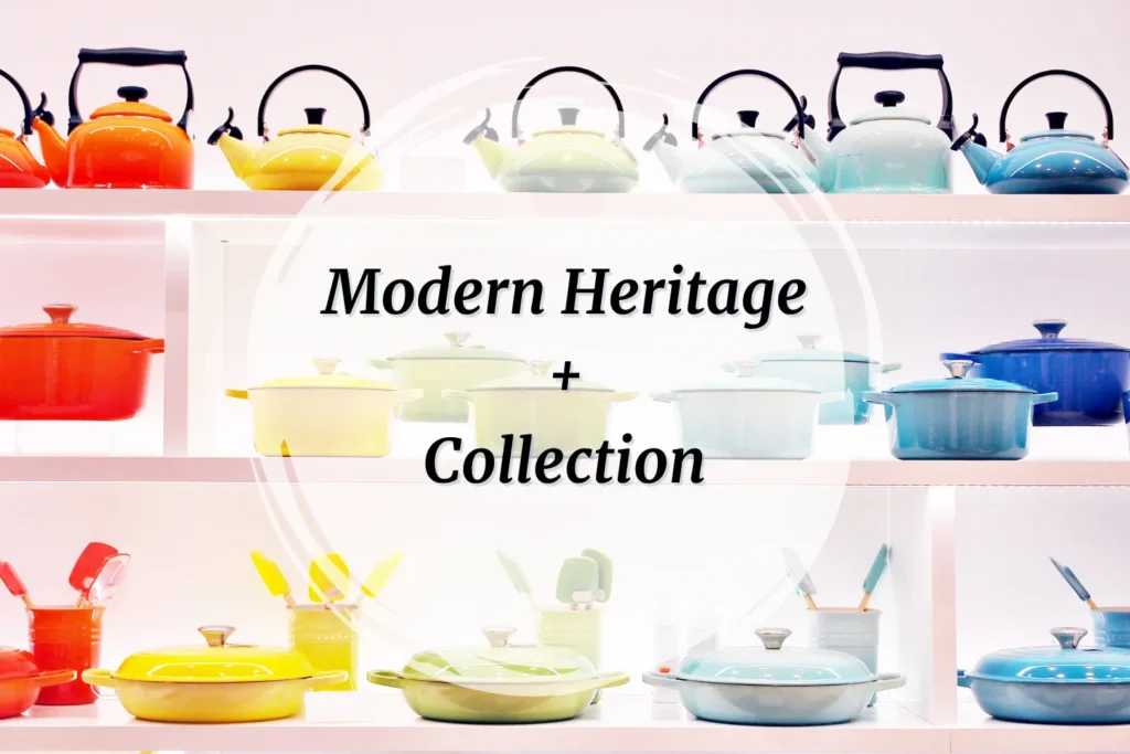 Le Creuset cookware displayed on white wood shelves in a rainbow of colors, with Modern Heritage and classic pieces styled together for a clean, editorial look.