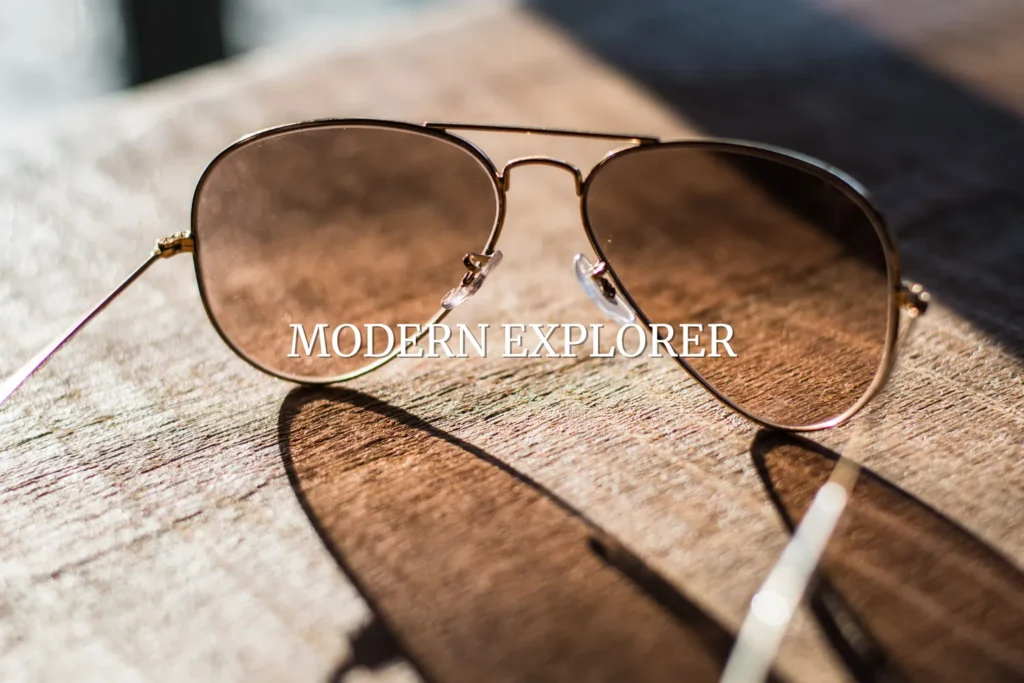 Close-up of aviator sunglasses on wooden surface in sunlight, representing Modern Explorer gifts for him.