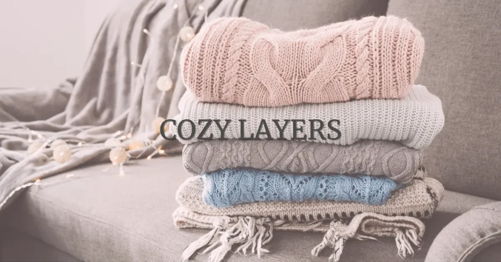 stack of soft neutral sweaters and blankets styled for cozy gift ideas